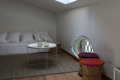 Ejemplo de salón tipo loft costero de tamaño medio con paredes blancas y suelo de madera clara