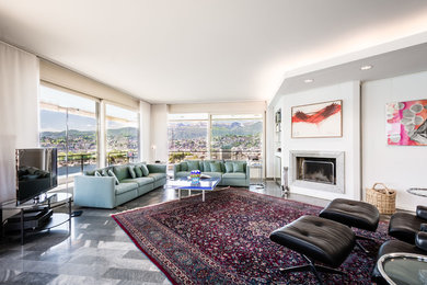 This is an example of an expansive contemporary open plan games room in Milan with white walls, marble flooring, a standard fireplace, a stone fireplace surround, a wall mounted tv and black floors.