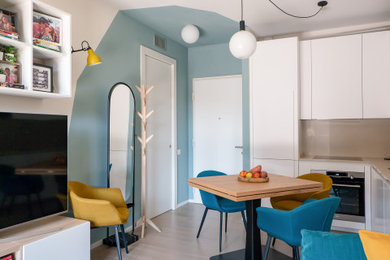 Small scandi open plan living room in Milan with a reading nook, multi-coloured walls, light hardwood flooring and a built-in media unit.