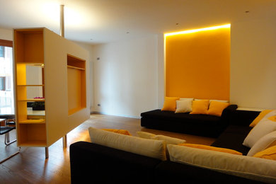 Ejemplo de salón actual con parades naranjas, suelo de madera pintada y pared multimedia