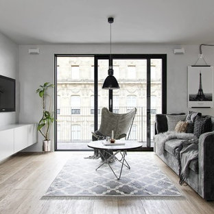 Immagine di un soggiorno scandinavo aperto con sala formale, pareti grigie, pavimento in legno massello medio, TV a parete e pavimento marrone