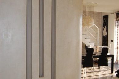 Modelo de salón abierto actual de tamaño medio con paredes beige, suelo de baldosas de porcelana, televisor colgado en la pared y suelo gris