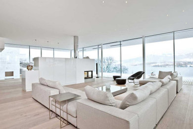 Idee per un ampio soggiorno moderno stile loft con parquet chiaro, camino bifacciale, cornice del camino in metallo e pavimento marrone