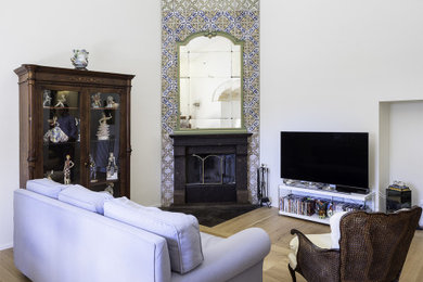Ejemplo de sala de estar contemporánea con paredes blancas, suelo de madera clara, chimenea de esquina, marco de chimenea de baldosas y/o azulejos, pared multimedia y suelo beige