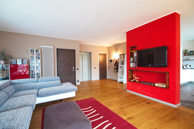 Foto de salón abierto moderno extra grande sin chimenea con paredes multicolor, suelo de madera en tonos medios, televisor colgado en la pared y suelo marrón