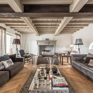 Idee per un soggiorno mediterraneo aperto con sala formale, pareti bianche, pavimento in legno massello medio, camino classico, cornice del camino in cemento e pavimento marrone