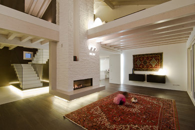 Foto di un ampio soggiorno design aperto con pareti bianche, parquet scuro, camino classico e cornice del camino in pietra