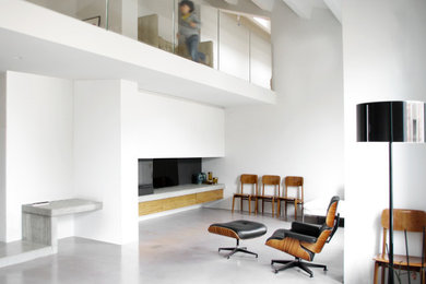 Mittelgroßes, Repräsentatives Modernes Wohnzimmer im Loft-Stil mit weißer Wandfarbe, Betonboden, Eckkamin, Kaminumrandung aus Metall, verstecktem TV und grauem Boden in Bologna