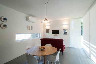 Diseño de salón abierto actual pequeño con paredes blancas, suelo de cemento y suelo gris