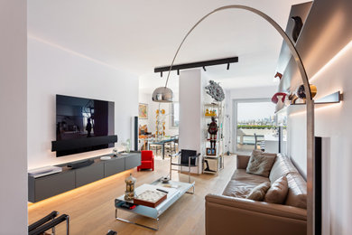 Modelo de salón con barra de bar abierto moderno grande con paredes blancas, suelo de madera clara y televisor colgado en la pared