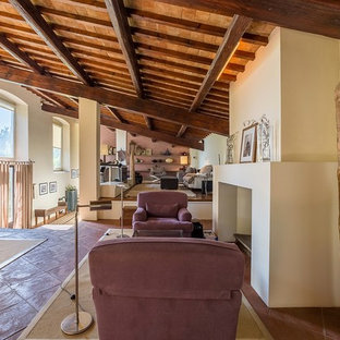 Immagine di un ampio soggiorno country con sala della musica, pareti bianche, pavimento in terracotta, camino classico, cornice del camino in pietra e parete attrezzata