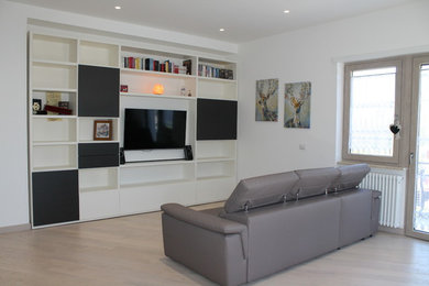 Immagine di un soggiorno moderno di medie dimensioni e aperto con libreria, pareti bianche, parquet chiaro, nessun camino, TV a parete e pavimento beige