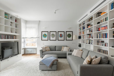 Imagen de salón actual con paredes blancas, suelo de madera en tonos medios, pared multimedia y suelo marrón