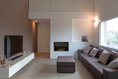 ヴェネツィアにある高級な広いコンテンポラリースタイルのおしゃれなLDK (グレーの壁、磁器タイルの床、横長型暖炉、漆喰の暖炉まわり、壁掛け型テレビ、グレーの床) の写真
