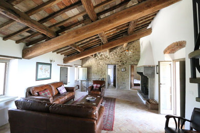 Ejemplo de salón campestre de tamaño medio con suelo de baldosas de terracota, todas las chimeneas y vigas vistas