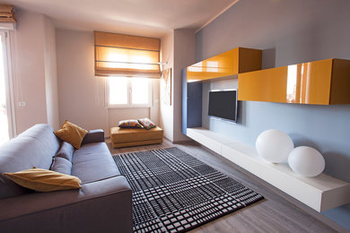 Ejemplo de sala de estar cerrada actual con paredes blancas, suelo de madera clara y televisor colgado en la pared