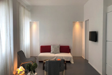 Foto de salón abierto contemporáneo pequeño con paredes blancas, suelo de cemento, televisor colgado en la pared y suelo gris