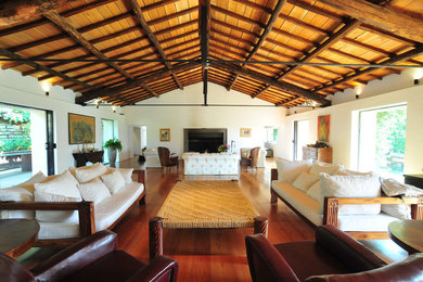 Modelo de sala de estar abierta de estilo de casa de campo extra grande con paredes blancas, suelo de madera en tonos medios, marco de chimenea de piedra, suelo marrón y madera
