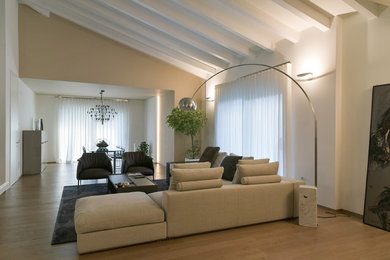 Immagine di un soggiorno contemporaneo con pareti beige, pavimento in legno verniciato, camino classico e cornice del camino in intonaco