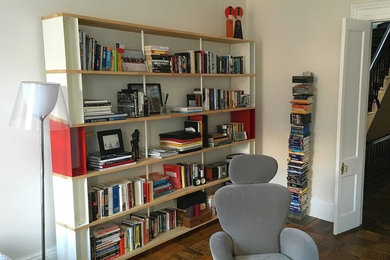Esempio di un soggiorno design di medie dimensioni con libreria, pareti bianche e pavimento in legno massello medio