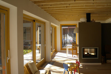 Foto di un soggiorno minimal di medie dimensioni e aperto con pareti bianche, parquet chiaro, camino bifacciale, cornice del camino in intonaco e pavimento beige