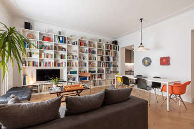Immagine di un grande soggiorno minimal con libreria, pareti bianche, pavimento in legno massello medio, TV autoportante e pavimento marrone