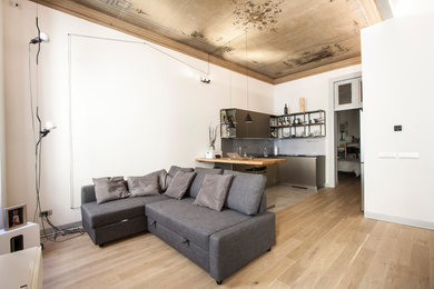 Esempio di un grande soggiorno minimalista stile loft con pareti bianche, parquet chiaro e TV a parete