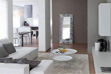 Esempio di un grande soggiorno minimalista aperto con libreria, pareti grigie, parquet chiaro, TV a parete e pavimento beige