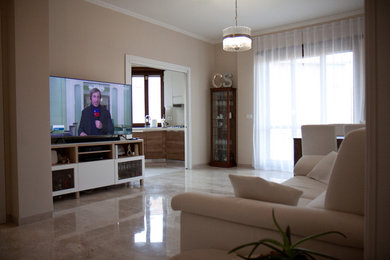 Ispirazione per un piccolo soggiorno moderno chiuso con pareti beige, pavimento in marmo, pavimento beige e TV a parete