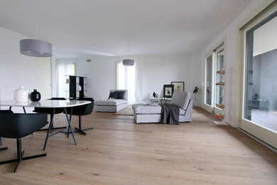 Design ideas for a large modern open plan living room in Milan with white walls and light hardwood flooring.