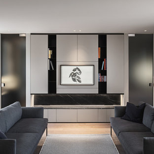 Foto di un piccolo soggiorno design aperto con libreria, pareti grigie, TV a parete, pavimento grigio e soffitto ribassato