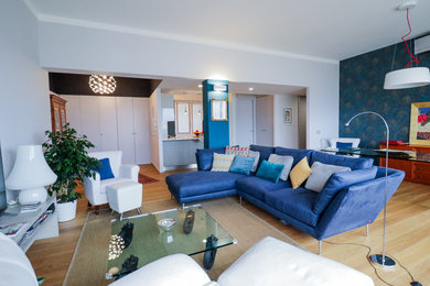 Immagine di un grande soggiorno minimalista aperto con pareti grigie, pavimento in legno massello medio, TV autoportante e pavimento marrone