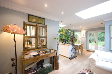 Imagen de sala de estar abierta ecléctica de tamaño medio con suelo de madera clara y suelo beige