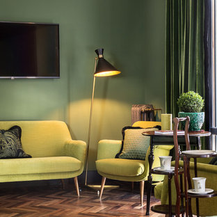Idee per un soggiorno bohémian con pareti verdi, parquet scuro e TV a parete