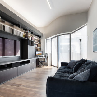 Immagine di un soggiorno design chiuso con pareti grigie, pavimento in legno massello medio, parete attrezzata e pavimento marrone