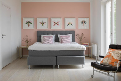 Diseño de dormitorio principal actual de tamaño medio sin chimenea con paredes rosas y suelo de madera clara