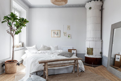 Mittelgroßes Skandinavisches Hauptschlafzimmer mit grauer Wandfarbe, hellem Holzboden, Eckkamin und beigem Boden in Stockholm