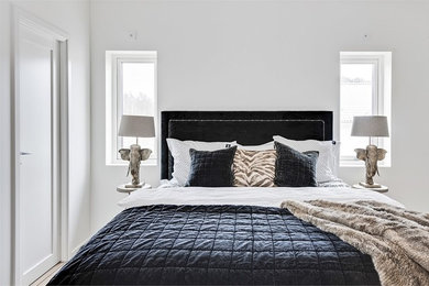 ヨーテボリにあるトランジショナルスタイルのおしゃれな客用寝室 (白い壁、淡色無垢フローリング、ベージュの床) のインテリア