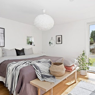 Foto på ett skandinaviskt sovrum, med vita väggar och ljust trägolv
