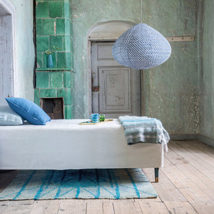 Ejemplo de habitación de invitados tradicional renovada, de tamaño medio, con suelo de madera clara, paredes verdes, chimenea de esquina y marco de chimenea de baldosas y/o azulejos