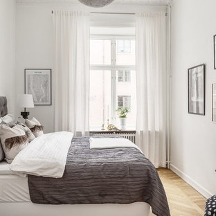Nordisk inredning av ett gästrum, med vita väggar, ljust trägolv och beiget golv