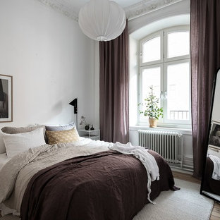 Bild på ett minimalistiskt sovrum, med vita väggar, ljust trägolv och beiget golv