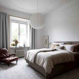 Foto på ett minimalistiskt sovrum, med vita väggar, heltäckningsmatta och grått golv