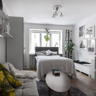 Minimalistisk inredning av ett mellanstort huvudsovrum, med vita väggar, ljust trägolv och beiget golv