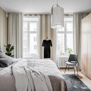 Foto på ett mellanstort nordiskt huvudsovrum, med flerfärgade väggar, ljust trägolv och beiget golv