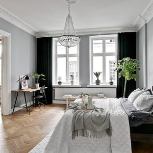 Foto på ett minimalistiskt huvudsovrum, med grå väggar, mellanmörkt trägolv och beiget golv