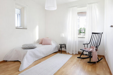 Diseño de habitación de invitados escandinava con paredes blancas, suelo de madera en tonos medios y suelo beige