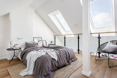 Ejemplo de dormitorio principal escandinavo de tamaño medio sin chimenea con paredes blancas y suelo de madera en tonos medios