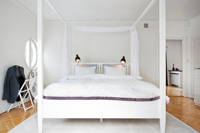 Foto på ett stort minimalistiskt huvudsovrum, med vita väggar och ljust trägolv
