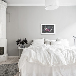 Minimalistisk inredning av ett mellanstort huvudsovrum, med grå väggar, ljust trägolv, en öppen hörnspis, en spiselkrans i trä och grått golv